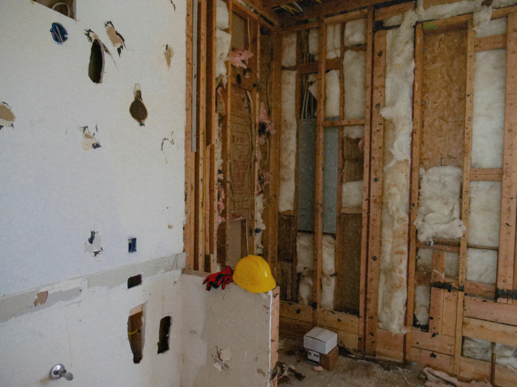 Exposed wall framing and insulation during renovation, showing hidden structural issues in a distressed property.