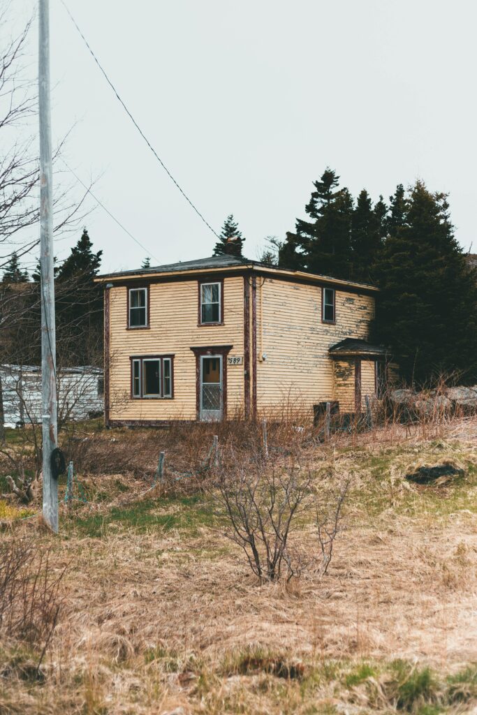 small distressed house with an overgrown yard showing a misleading real estate investment opportunity that beginners may underestimate