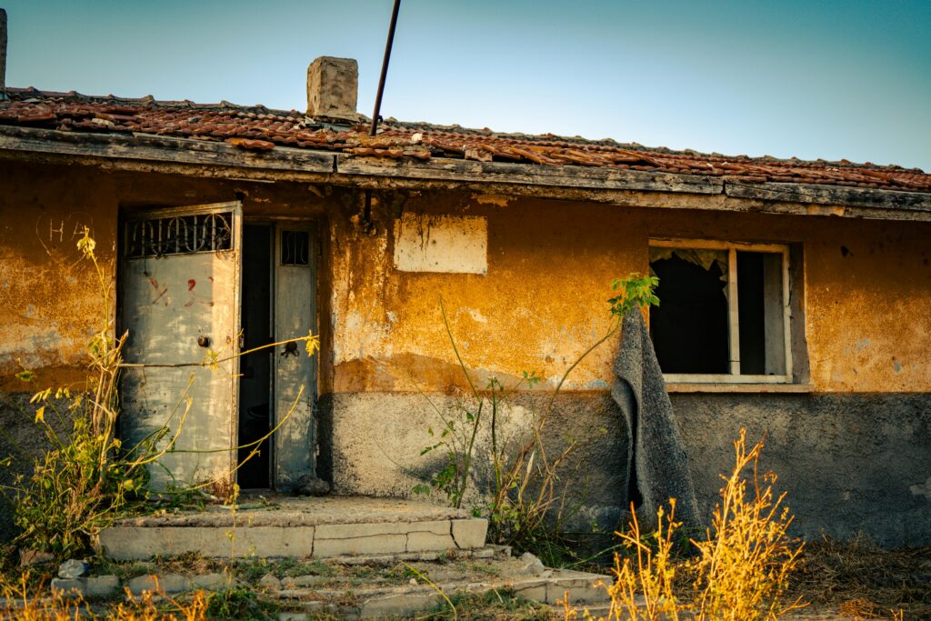Distressed property with visible neglect, broken windows, and exterior deterioration, illustrating the hidden risk of distressed real estate investing.